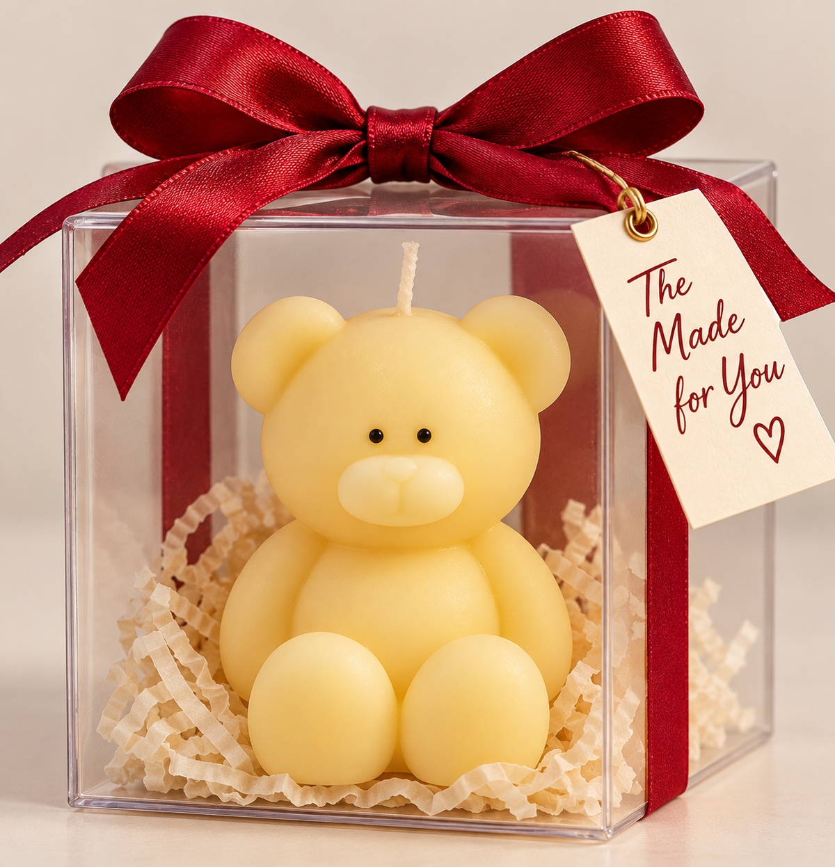 Yellow teddy candle in a clear gift box with a red ribbon and gift tag